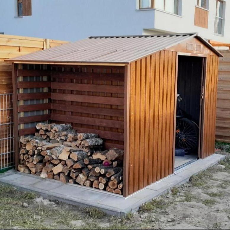 Blaszana drewutnia z domkiem przy ogrodzeniu